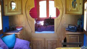 Un interior acogedor con un arco de madera, una cama con ropa de cama púrpura y una mesita con un radio.