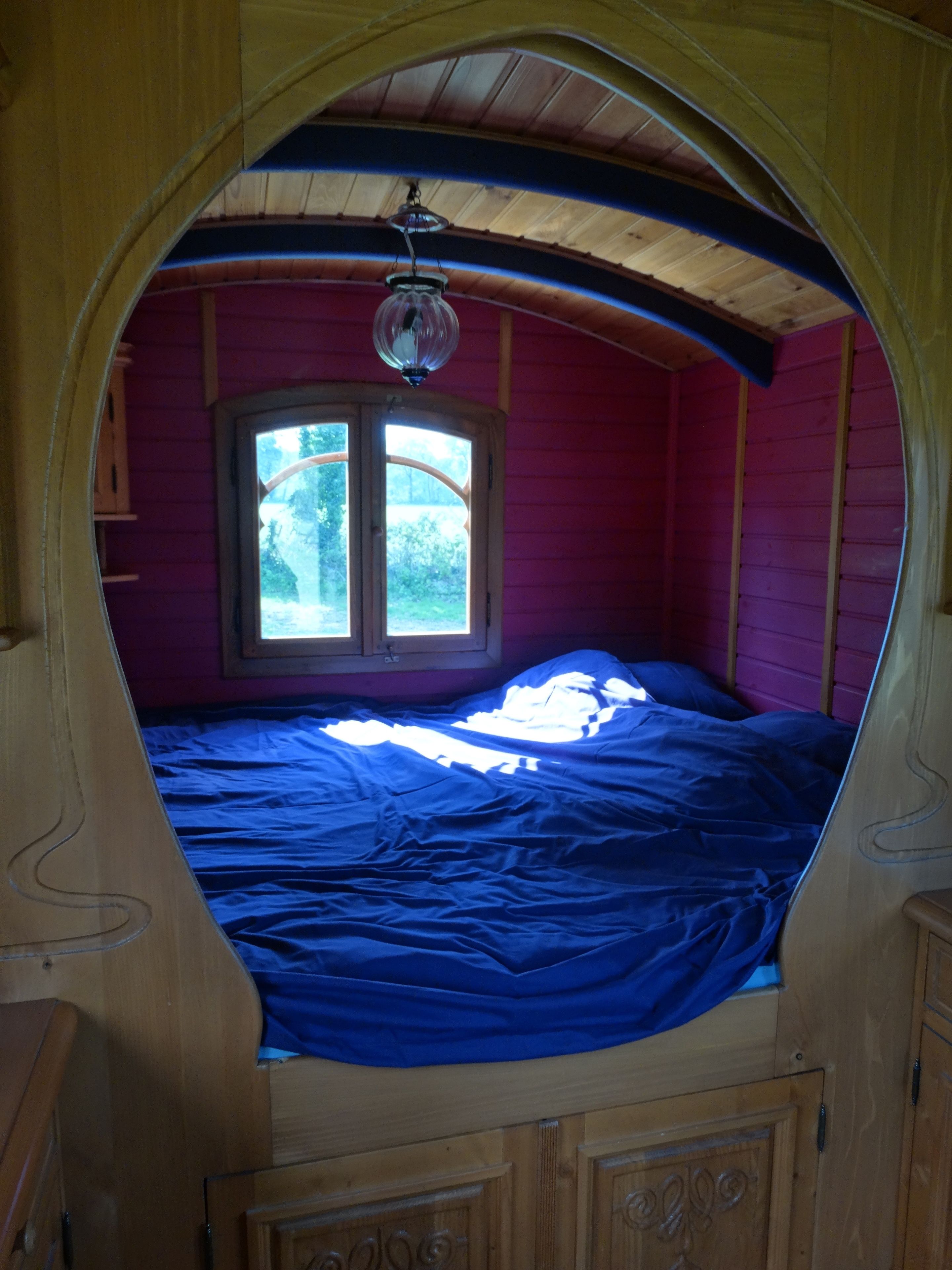 Ein Schlafzimmer mit Bett, Fenster und einer Pendelleuchte.