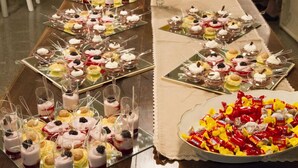 A buffet table with various desserts and snacks, including mini cakes, fruit tarts, and a large bowl of assorted candies. - Hotel Europa (Viadana)