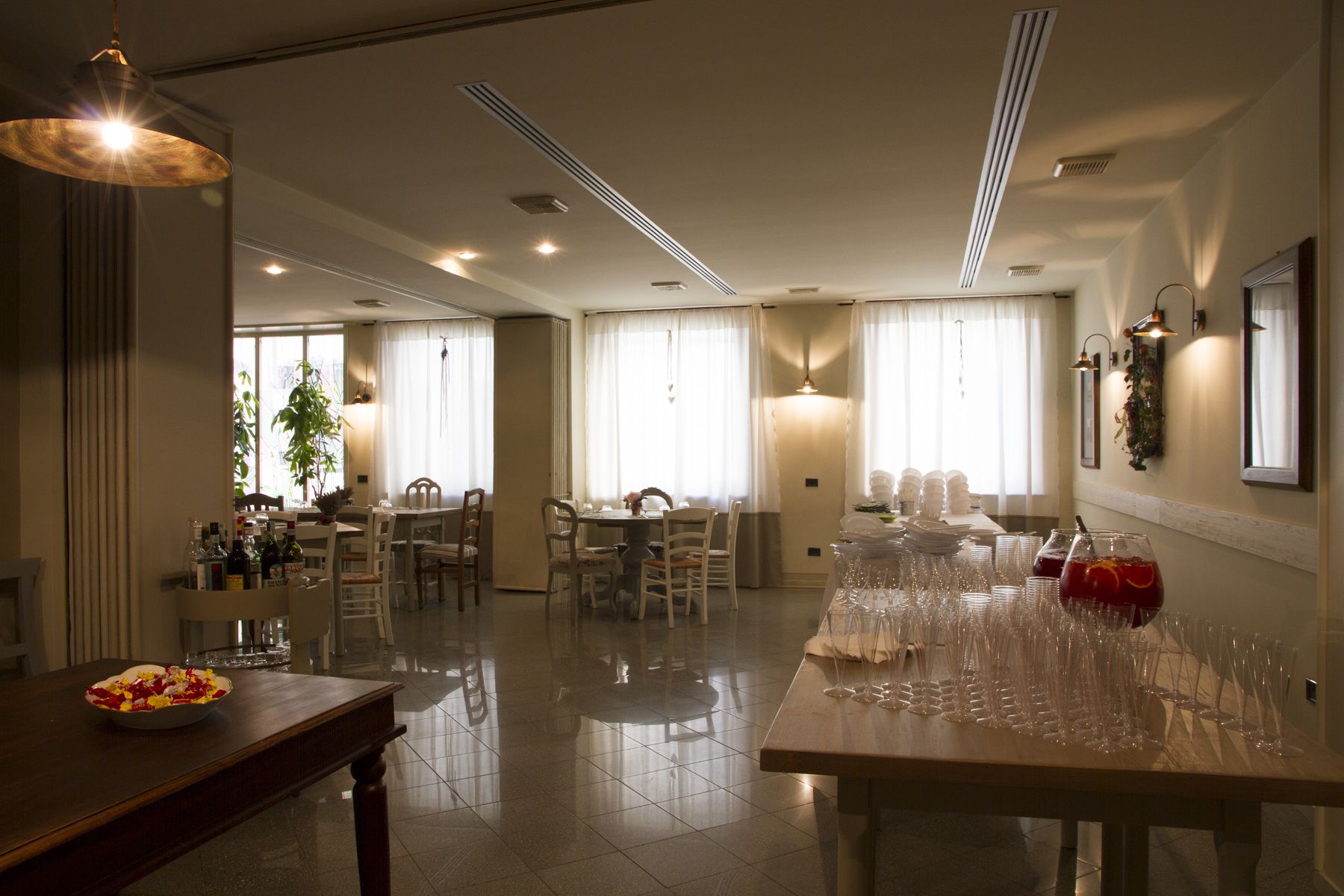 Spaziosa sala da pranzo di un hotel, con numerosi tavoli, sedie e diversi tipi di bicchieri.