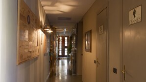 A hotel corridor with a wooden bulletin board, a sign reading "FEMMES," and a door labeled "HOMMES." - Hotel Europa (Viadana)