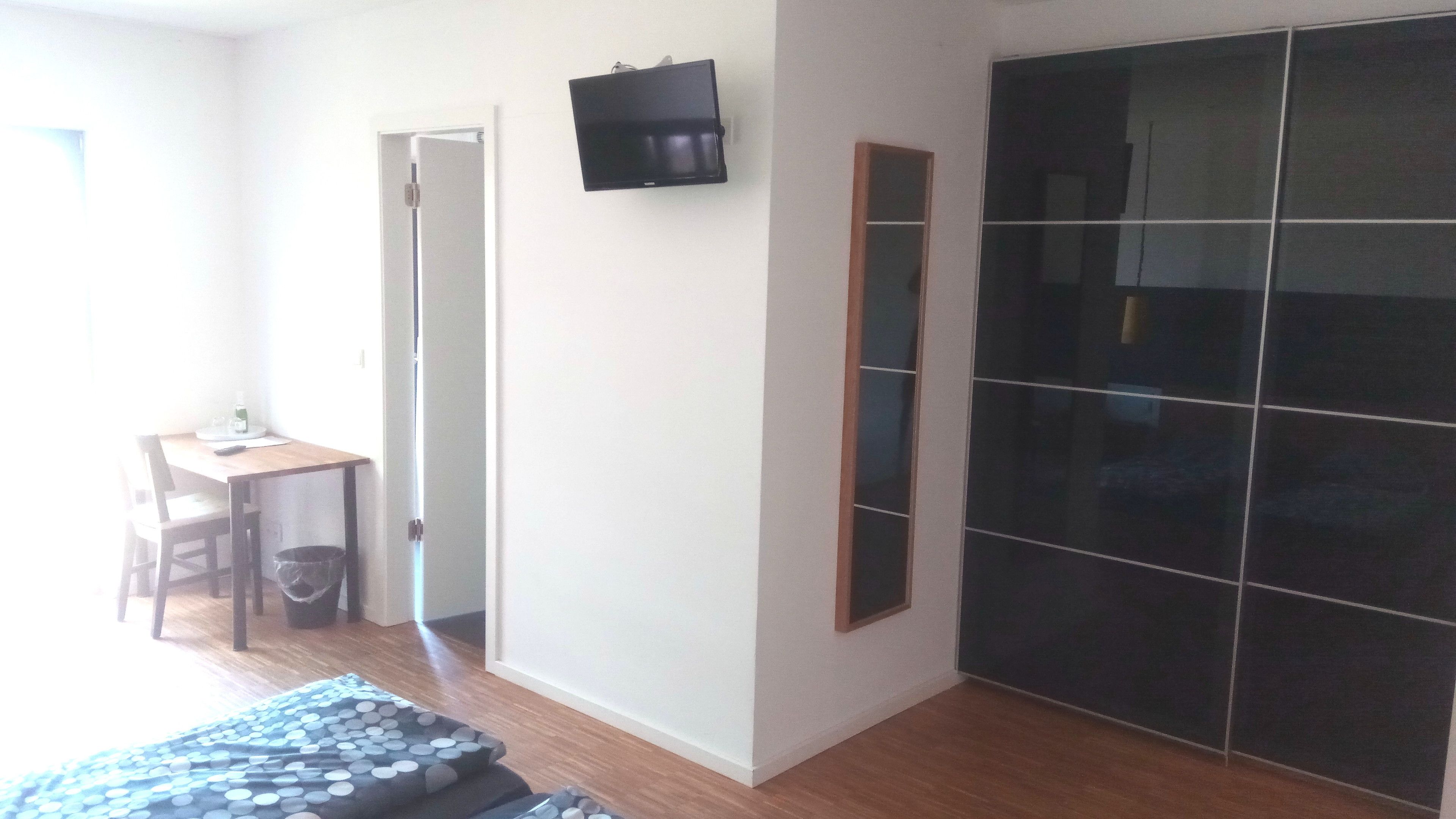 Una habitación con una cama, un escritorio, una silla, un televisor y un armario.
