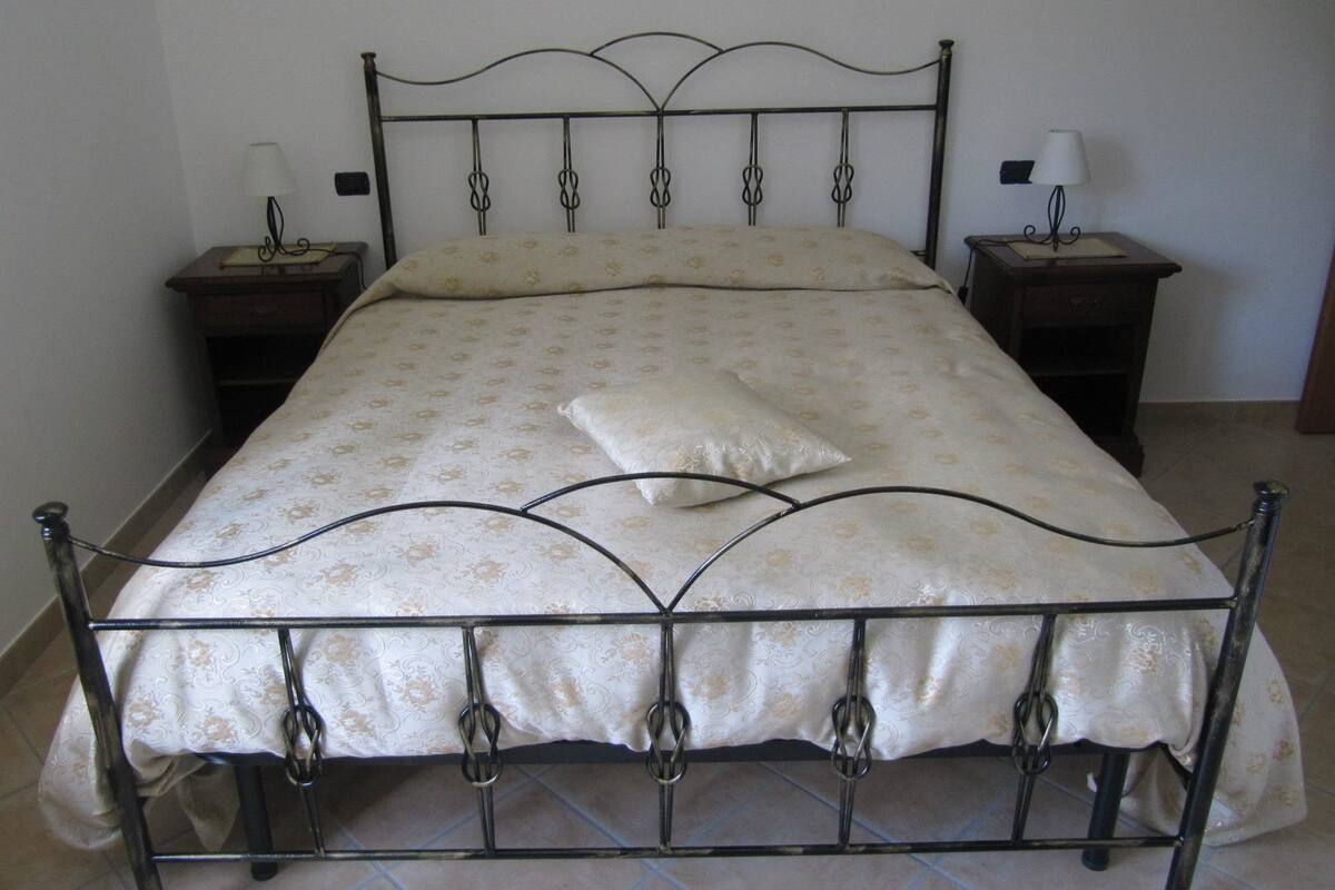 A bed with a metal frame, a floral bedspread, and two bedside tables with lamps.