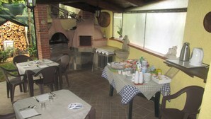 An outdoor patio area with tables set for dining, a brick oven, and a pizza oven.