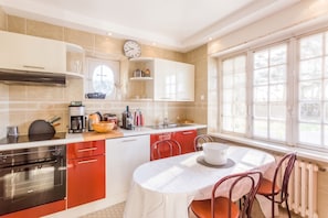 A modern kitchen with a dining area, equipped with appliances and a window providing natural light.