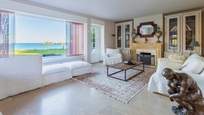 A spacious living room with a large window overlooking the sea, a fireplace, and a statue. - Homerez - Villa in Roscoff, sea view (Roscoff)