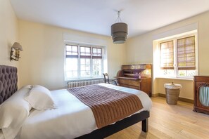 A bedroom with a bed, a dresser, a chair, a radiator, and a window with blinds. - Homerez - Villa in Roscoff, sea view (Roscoff)