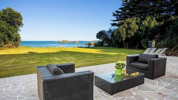 A patio with wicker furniture, a glass table, and a view of the sea. - Homerez - Villa in Roscoff, sea view (Roscoff)