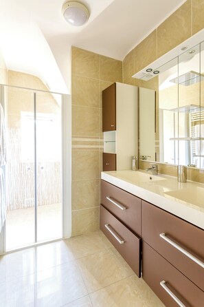 A modern bathroom with a large mirror, a sink, and a glass shower enclosure. - Homerez - Villa in Roscoff, sea view (Roscoff)