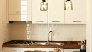 A modern kitchen with white cabinets, a wooden countertop, and two hanging pendant lights. - B&B In White (Rome)