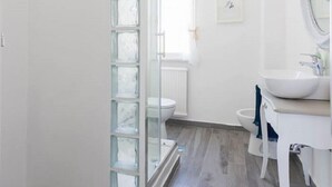 A modern bathroom with a glass shower enclosure, a white sink, and a large mirror. - B&B In White (Rome)
