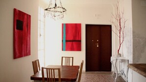 A dining area with a wooden table and chairs, a chandelier, and a red door. - B&B In White (Rome)