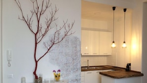 A modern kitchen with white cabinets, a wooden countertop, and pendant lighting. - B&B In White (Rome)