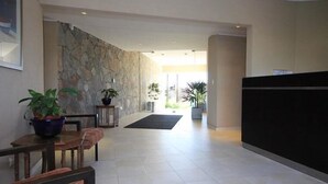 Spaziosa hall con parete in pietra, reception e piante in vaso.