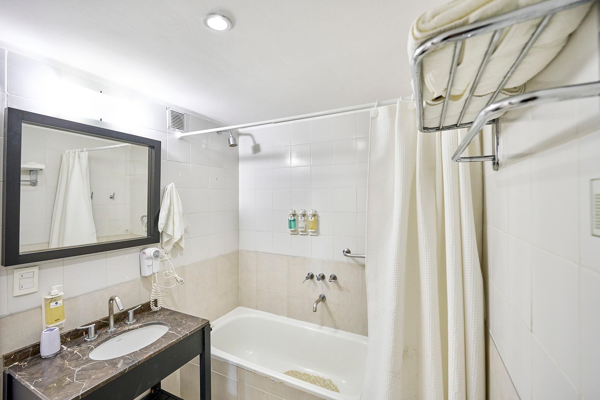 Un baño con bañera, lavamanos, espejo y cortina de ducha.
