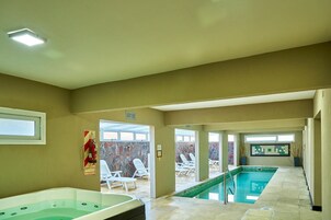 Una piscina interior con sillas de descanso y un jacuzzi.
