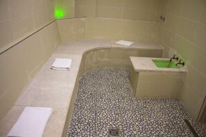A small, tiled bathroom with a shower, a sink, and a towel rack.