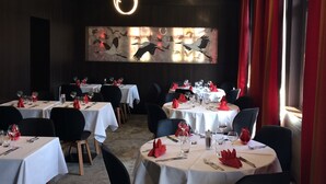 Comedor con mesas redondas, sillas negras y manteles blancos.