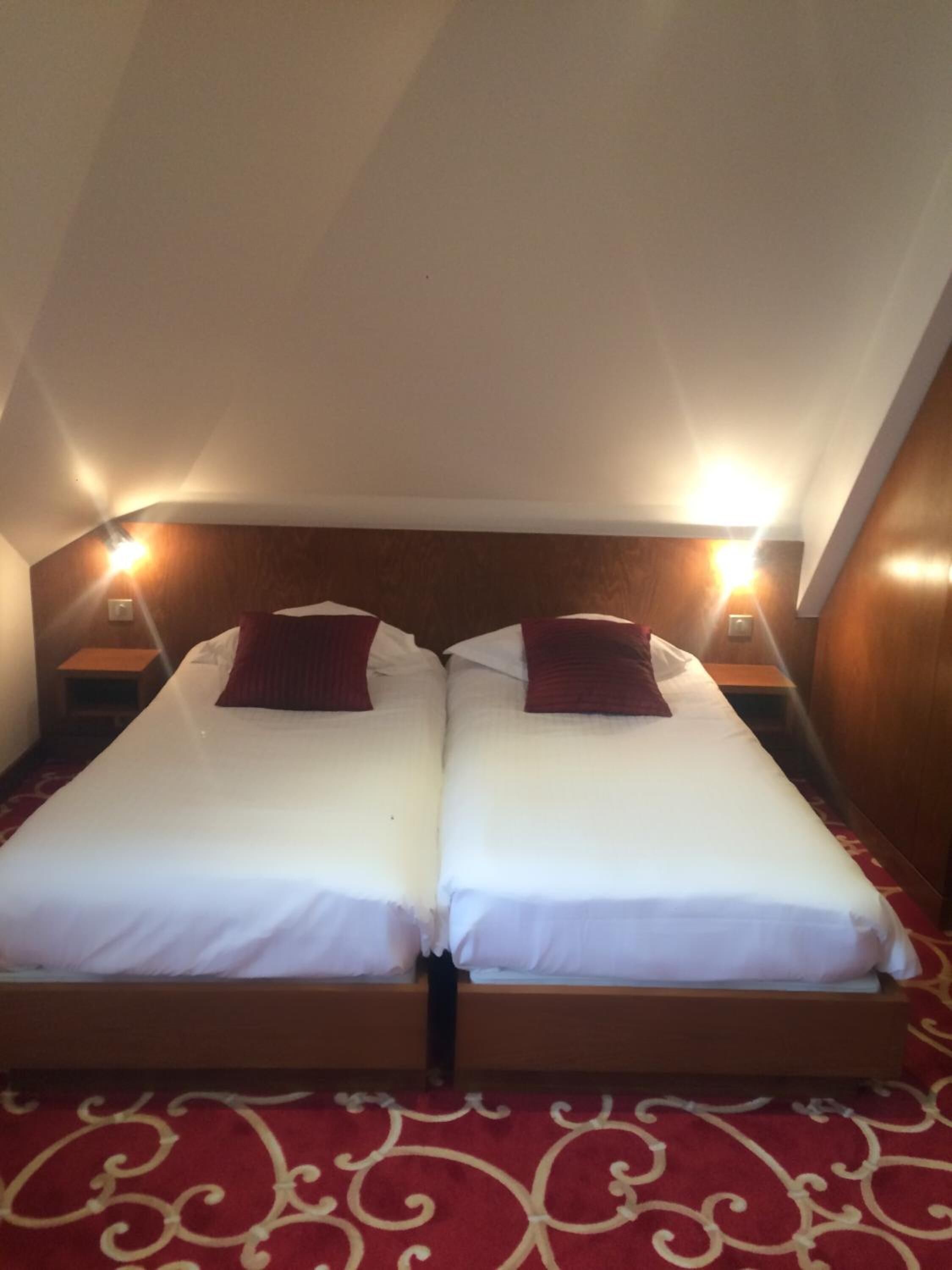 A twin room with two beds, wooden headboards, and nightstands with lamps.