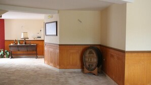 Un vestíbulo de hotel con un banco de madera, una mesita con una lámpara y un cuadro en la pared.