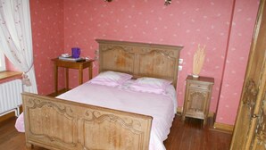 Un dormitorio con cama de madera, mesita de noche, cómoda y radiador.