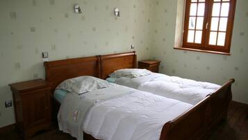 Un dormitorio con dos camas individuales, cabeceros de madera, mesitas de noche y una ventana con persianas.