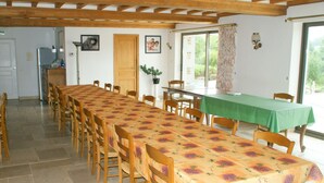 Comedor con una larga mesa cubierta por un mantel floral, rodeada de sillas de madera.