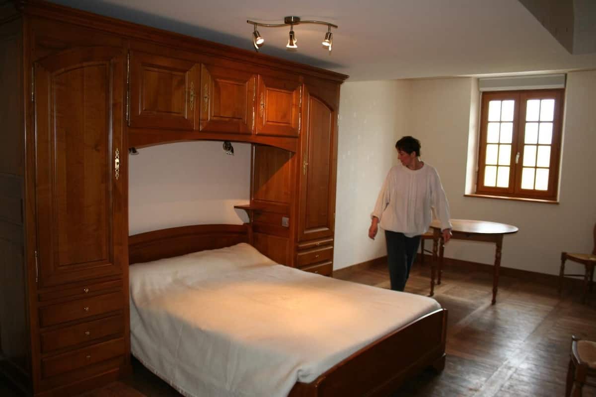 Une chambre à coucher avec un grand lit en bois, une armoire en bois et une petite table ronde.