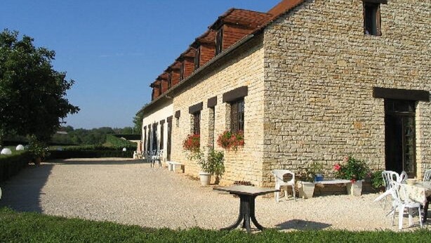 A stone building with a gravel driveway and outdoor seating area. - Domaine des Garennes (Nadaillac)