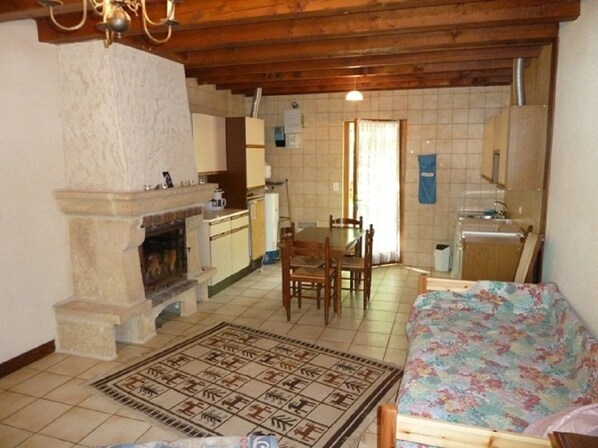 A compact living space with a stone fireplace, a dining area, and a kitchenette. - Domaine des Garennes (Nadaillac)