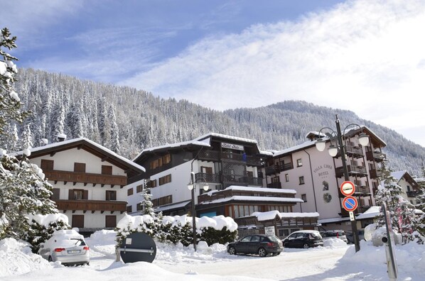 A hotel with a traditional Alpine architectural style, featuring multiple balconies and a snow-covered landscape. - Italo (Tre Ville)
