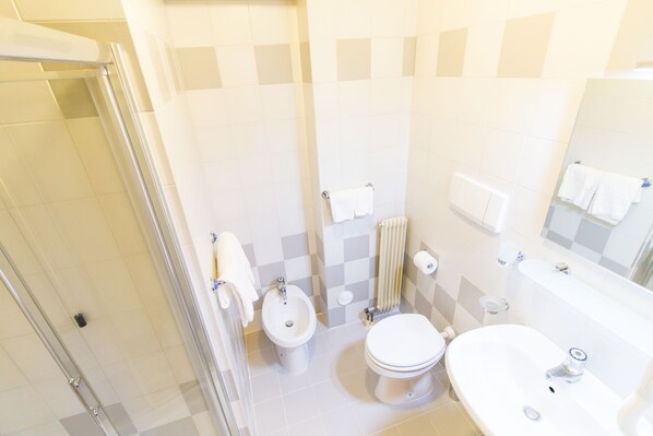 A modern bathroom with a glass shower enclosure, a toilet, bidet, and a sink. - Italo (Tre Ville)