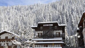 Ett hotell i traditionell alpnisk stil, med en träbalkong och en skylt som visar texten ”Hotel Halo”.