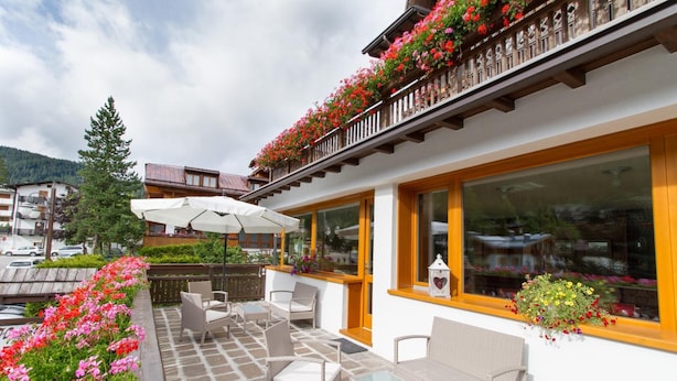 En hotellterrass med möbler av rotting, stora fönster och blomlådor.