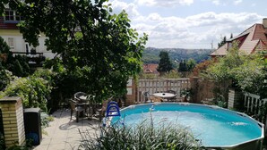 Piscina cercada por vegetação, com vista para o horizonte urbano ao fundo.