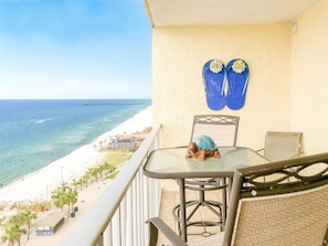 Ein Balkon mit Tisch und Stühlen mit Blick auf Strand und Meer.