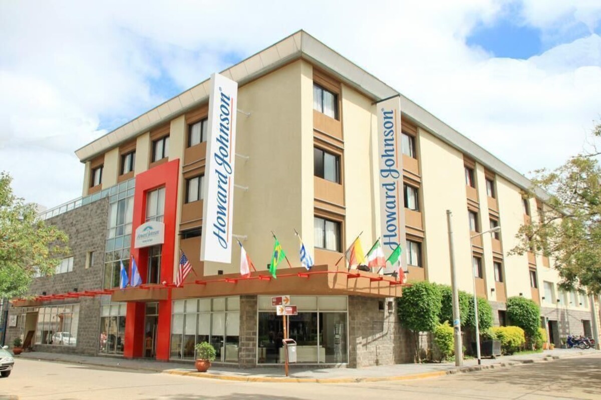 A hotel with a modern facade, multiple flags, and a prominent entrance.