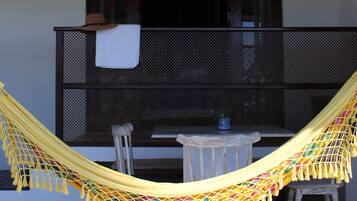 A balcony with a hammock, a small table, and a chair.