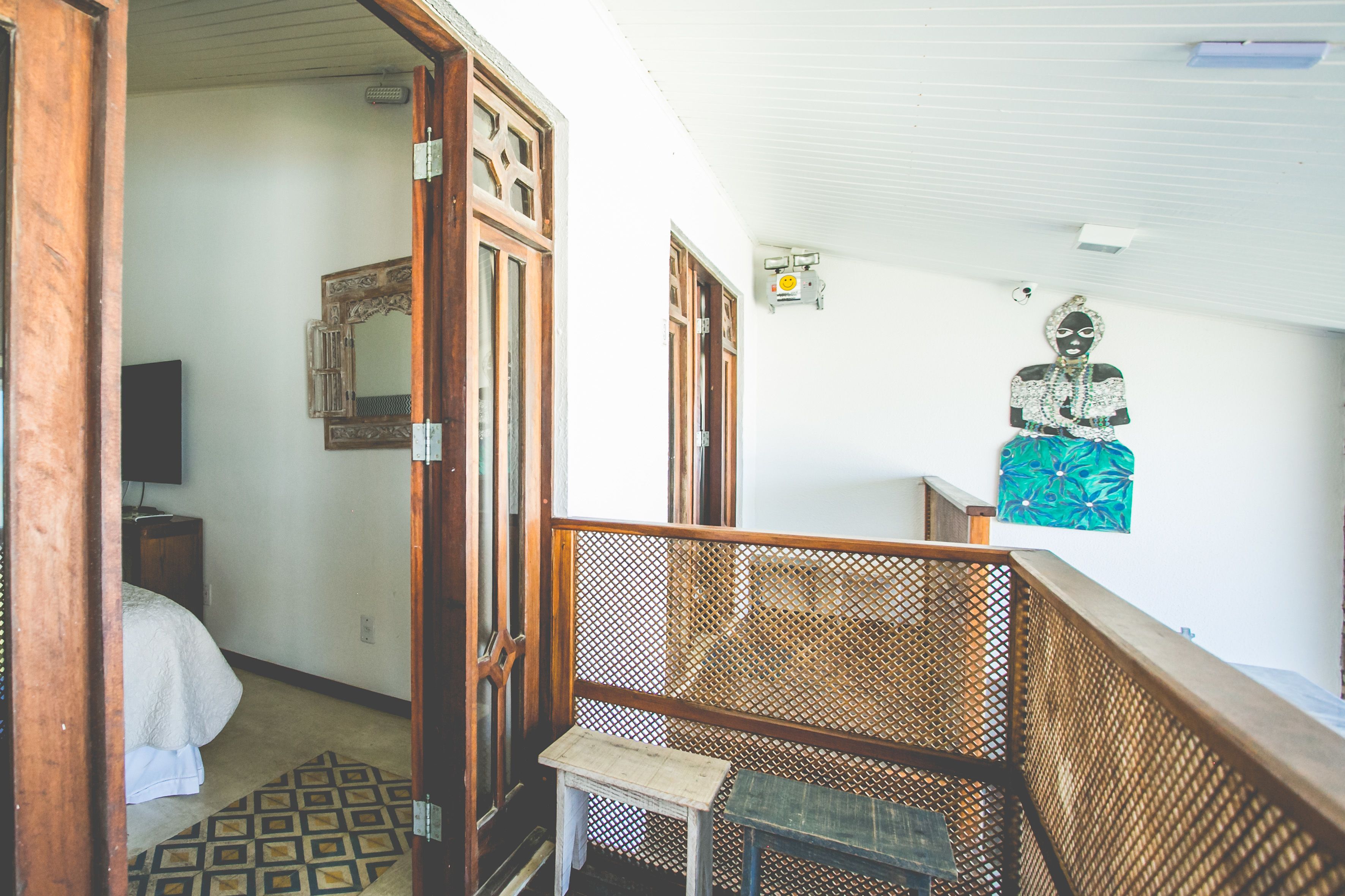Ein Zimmer mit einem Bett, einem kleinen Tisch, einem Holzgeländer und einer an der Wand befestigten Buddha-Statue.