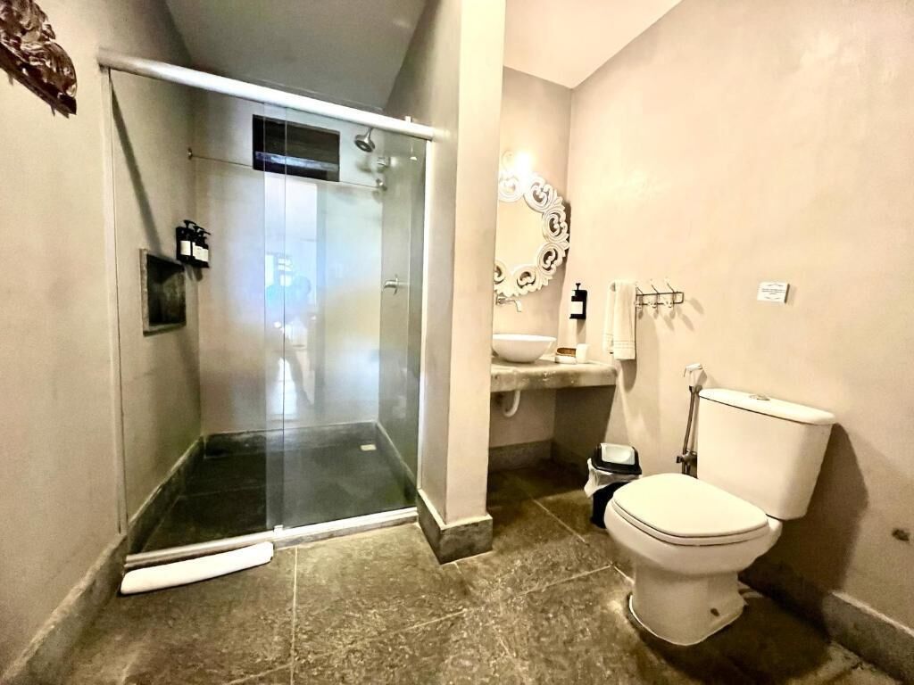 Un baño con cabina de ducha de vidrio, un inodoro, un lavabo y un espejo.