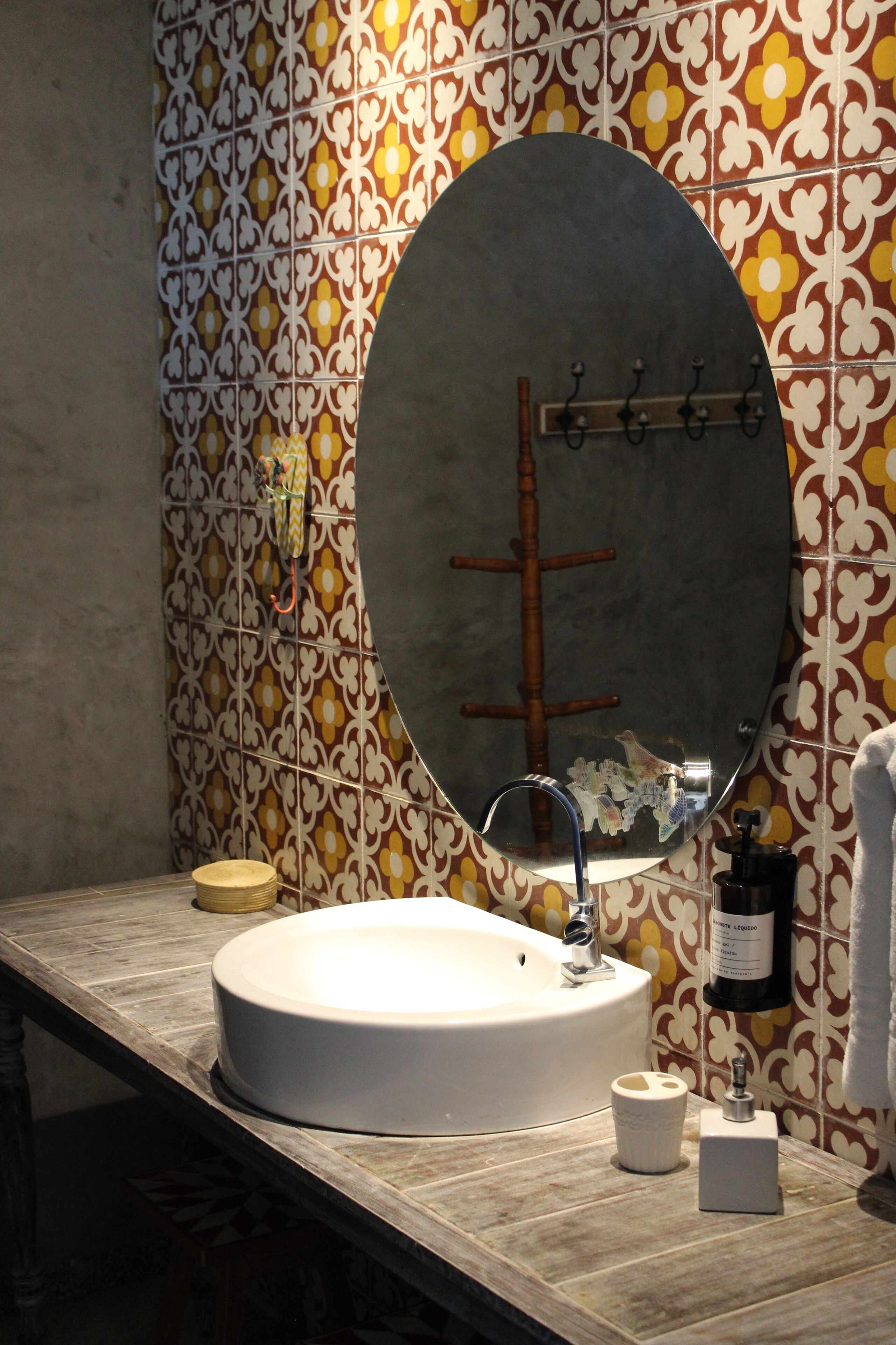 Un baño con un espejo redondo, un lavamanos y una pared con diseño.
