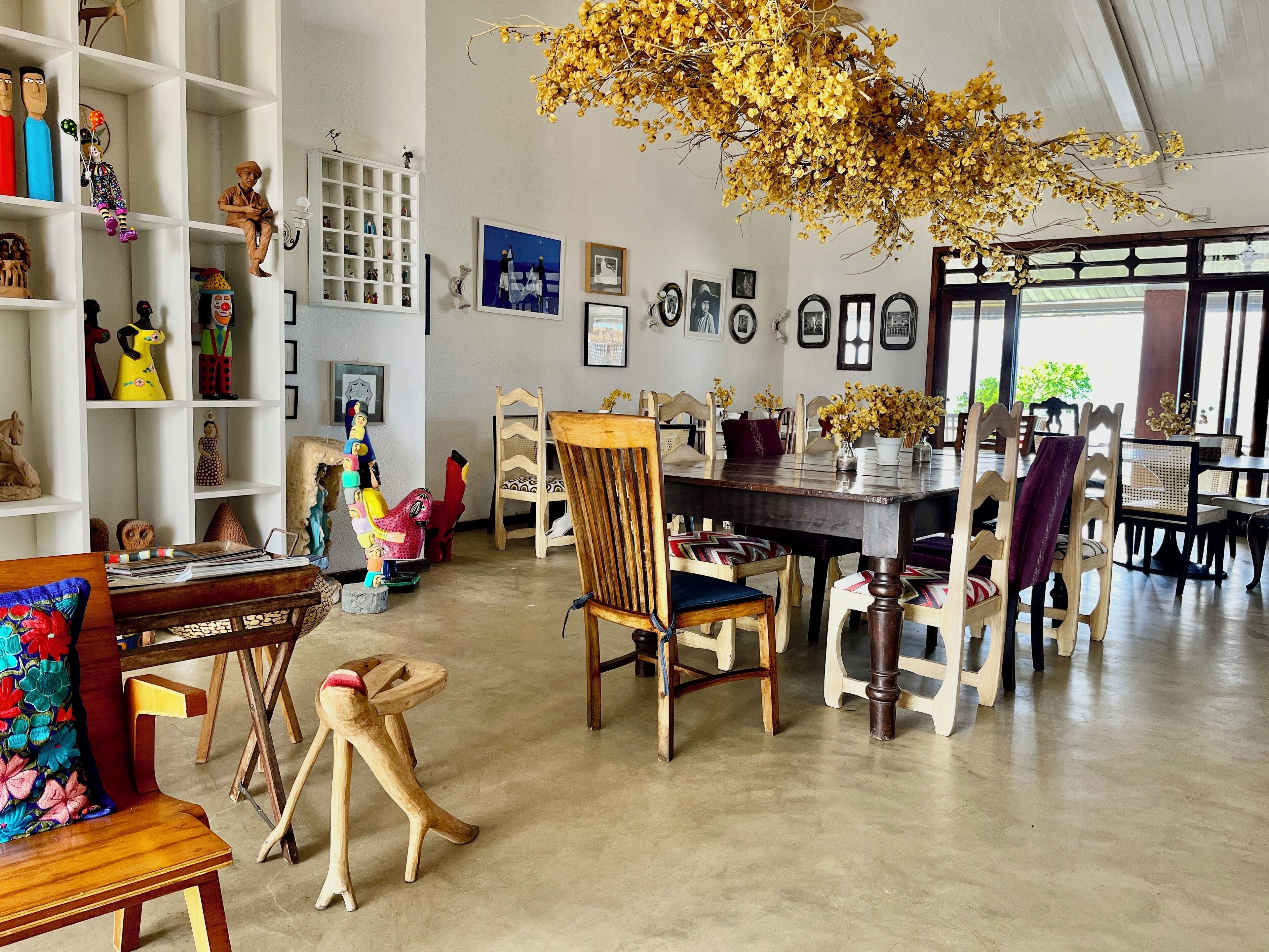 A dining area with a wooden table and chairs, surrounded by shelves with various decorative items.