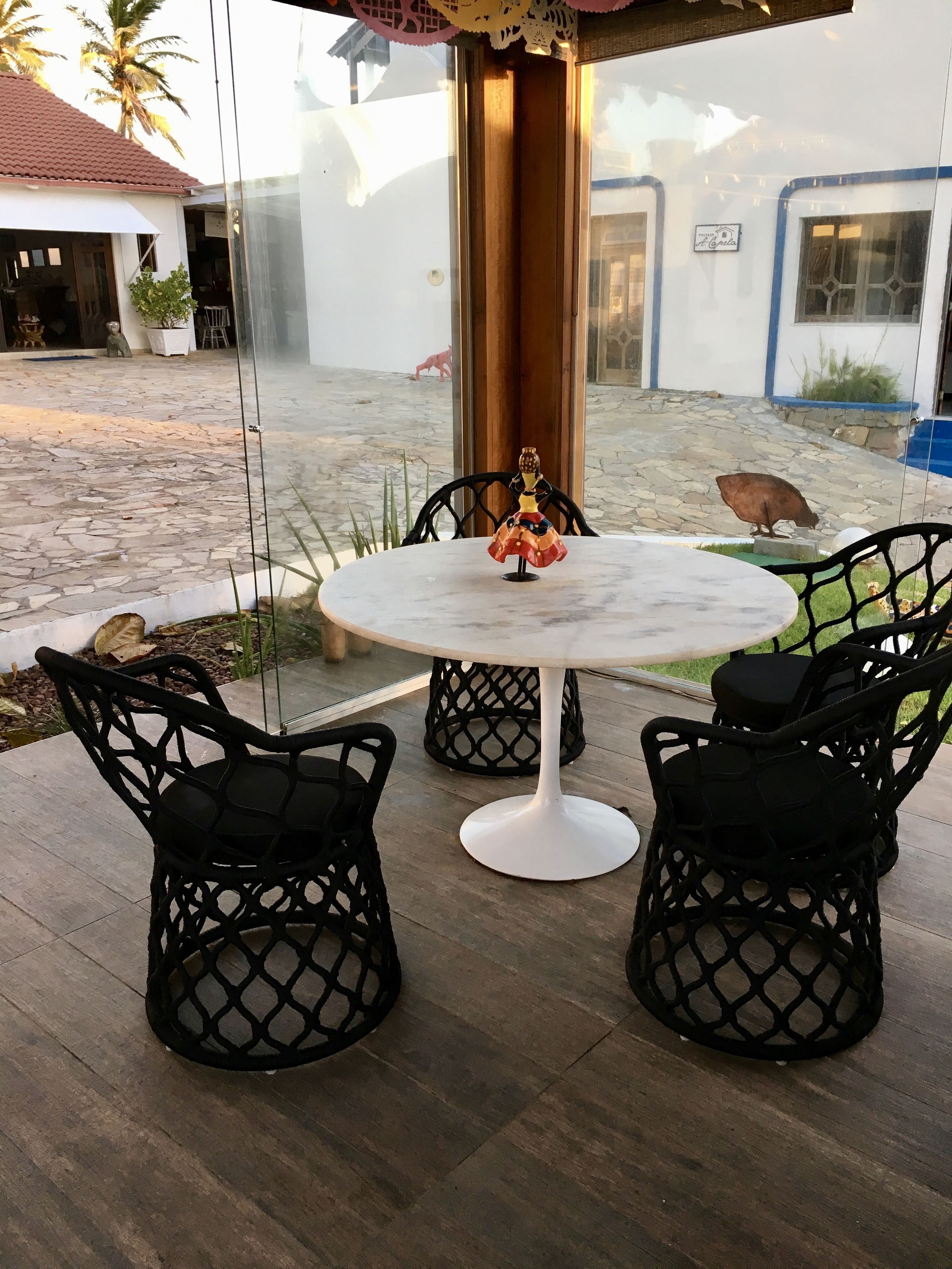A patio area with a round table and four chairs, a statue, and a view of a building with a sign that reads "Casa".