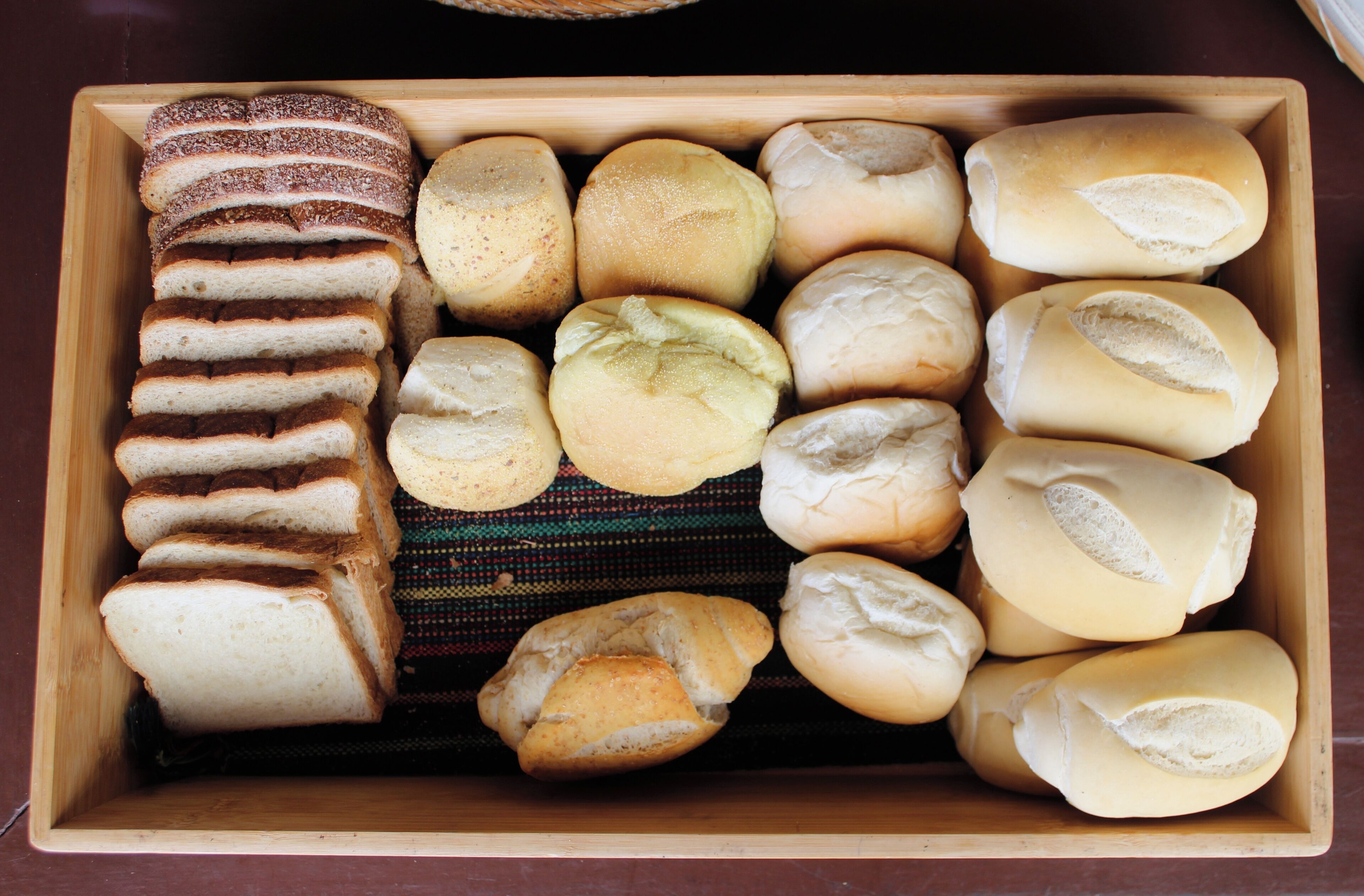 A wooden box containing various types of bread.