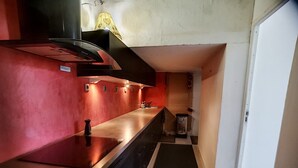 Una cocina compacta con pared roja, encimera negra y campana extractora de acero inoxidable.