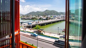 A view from a balcony overlooking a river with a bridge, buildings, and mountains in the distance. - Moonlight Bay Hotel (Bac Nha Trang)