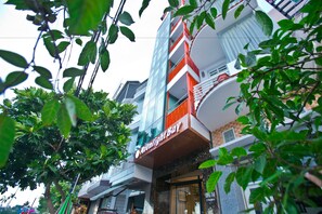 A multi-story building with balconies, a visible sign reading "Moonlight Bay," and a tree in the foreground. - Moonlight Bay Hotel (Bac Nha Trang)