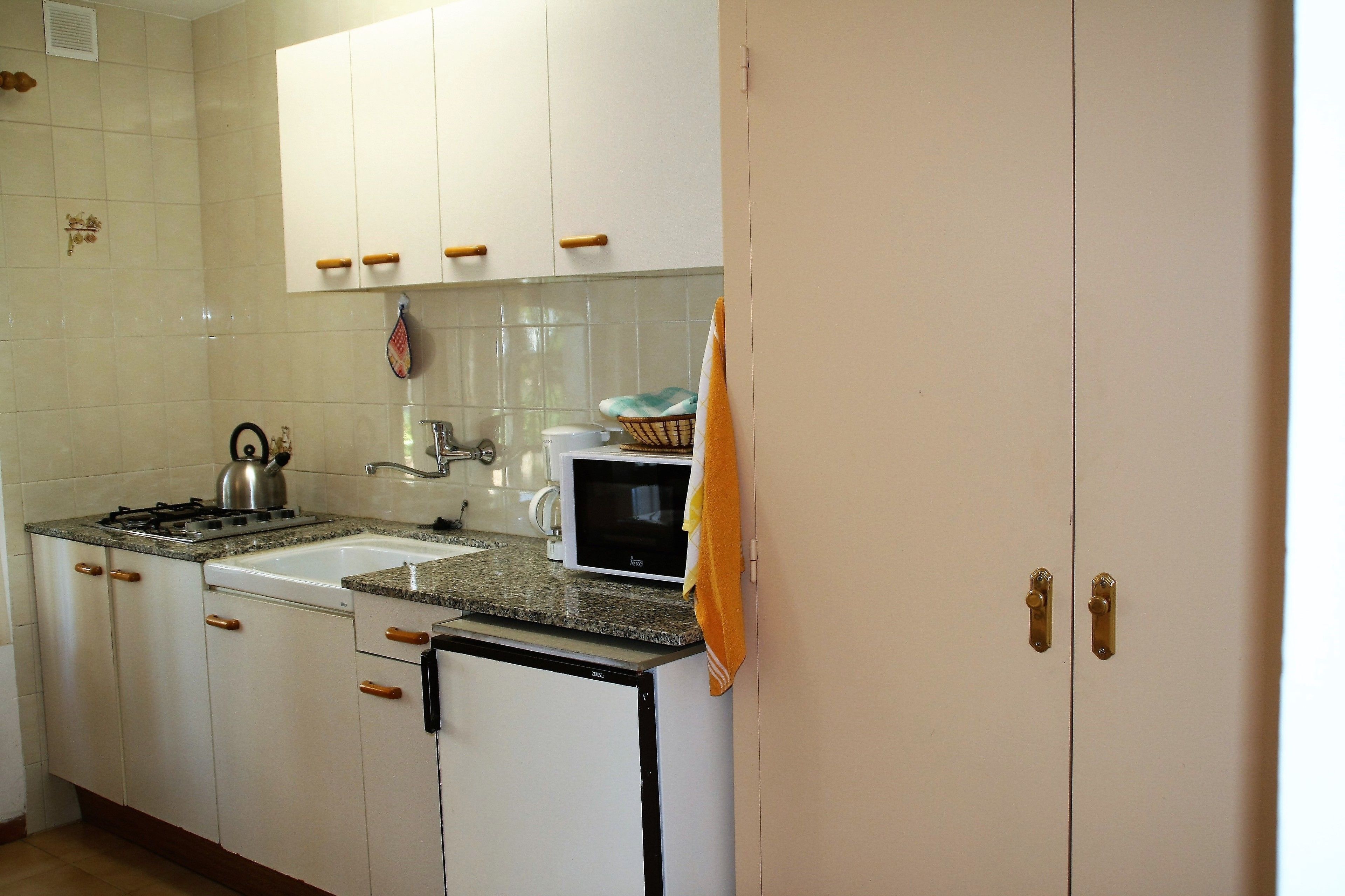 A kitchen with white cabinets, a stove, a sink, and a microwave.