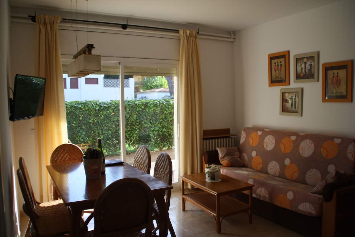 Una sala de estar con sofá, mesa de comedor, sillas y televisor.