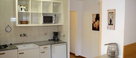 A kitchen with white cabinets, a microwave, a coffee maker, and a sink.